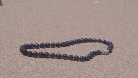 Moving-around-a-Perl-Jewellery-necklace-on-sand-slow-motion-120-FPS-shot