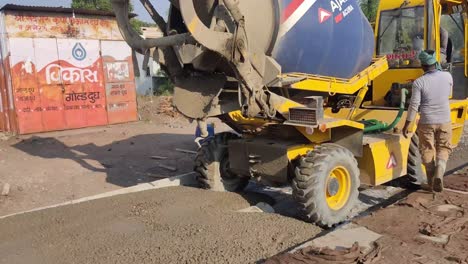 A-construction-worker-pouring-wet-concrete-at-the-road-construction-site-by-concrete-mixer-lorry