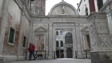 Viejo-Varón-Paseando-A-Su-Perro-Por-El-Patio-De-La-Scuola-Grande-Di-San-Giovanni-Evangelista-En-Venecia