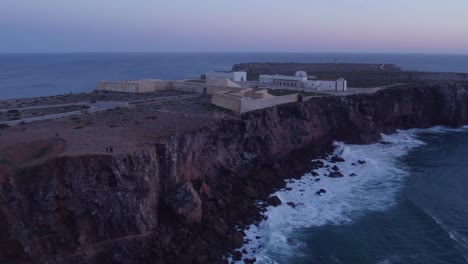 Wide-shot-of-Sagres-Fortress-Portugal-on-high-cliff-during-sunset,-aerial