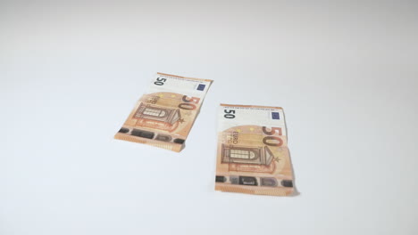 Fallende-Euro-Banknoten-In-Zeitlupe-Auf-Einem-Weißen-Hintergrundtisch