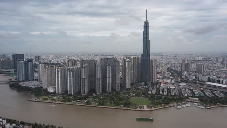 Saigon-Fluss-Hyperlapse-Oder-Zeitraffer-Aus-Der-Luft-Mit-Markanten-Gebäuden,-Containerschiffen-Und-Der-Skyline-Von-Ho-Chi-Minh-Stadt-Aus-Einem-Dramatischen-Hohen-Winkel-Mit-Sich-Bewegenden-Wolken-Am-Himmel