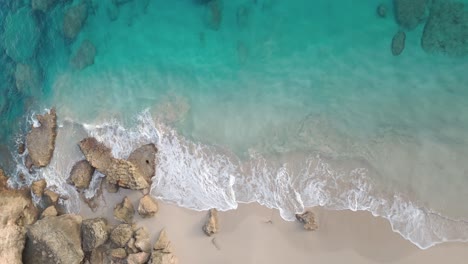 Aerial-top-down-shot-of-rocks-on-sandy-beach-and-arriving-waves-of-Caribbean-sea---Playa-Chencho,-Dominican-Republic
