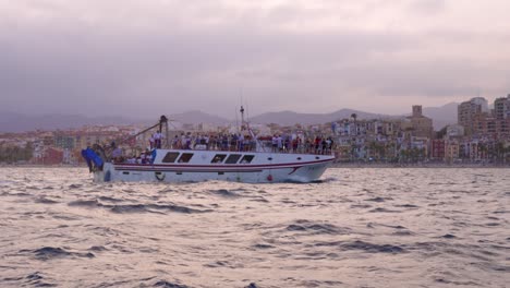Main-boat-in-the-maritime-procession-of-the-Virgen-del-Carmen-in-Villajoyosa,-Alicante,-Spain,-in-the-background-the-colourful-houses