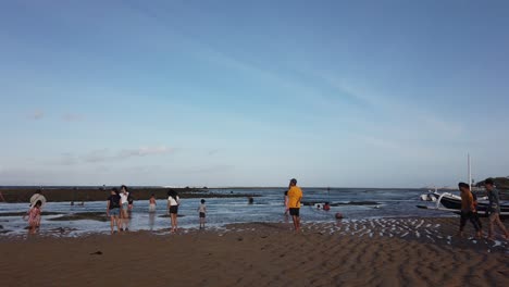 Indonesian-People-Enter-the-Low-Tide-Calm-Sea-at-Sanur-Beach-Bali-Indonesia-Blue-Skyline,-Natural-Beautiful-Travel-Destination