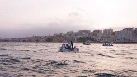 Kleine-Boote-In-Der-Maritimen-Prozession-Von-Villajoyosa-Mit-Bunten-Häusern-Im-Hintergrund