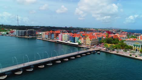 4k-drone-backwards-reveal-fly-away-of-stunning-Willemstad-city,-featuring-the-famous-colorful-UNESCO-buildings-of-the-Handelskade,-in-Punda,-Curacao