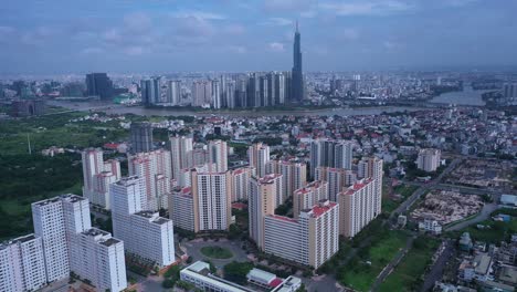 Aerial-fly-in-to-large-modern-residential-development-with-city-skyline-in-background-on-a-sunny-day-in-Ho-Chi-Minh-City,-Vietnam