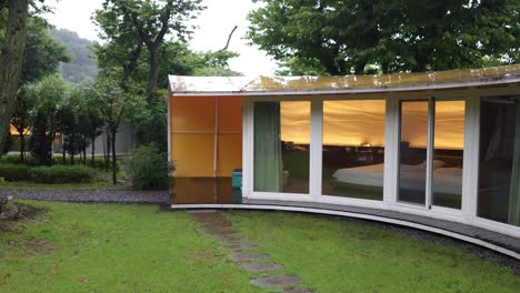 Moderne-Luxus-Glamping-Villa-Im-Wald-Mit-Geschwungenen-Panoramafensterwänden-An-Regnerischen-Tagen