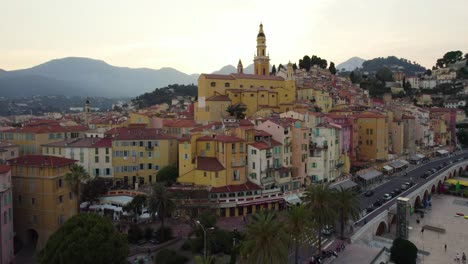 Colorful-Buildings-and-Church-Tower-in-Menton,-France-at-Sunset---Cinematic-Aerial-Drone-Flight