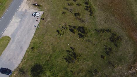 Aerial-top-down-view-of-a-white-car-parked-in-the-countryside-during-the-day