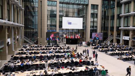 European-Council-press-room-in-the-Justus-Lipsius-building-crowded-with-journalists-during-the-European-Council-summit-in-Brussels,-Belgium---Panning-shot