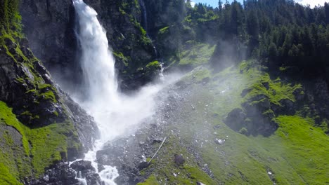 Mist-spray-from-waterfall-bounces-and-spreads-across-sky-from-staubifall,-Swiss-alps