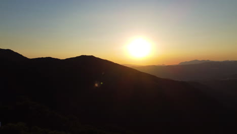 Die-Sonnenuntergänge-über-Den-Silhouetten-Der-Berge,-Während-Sich-Eine-Drohne-Zurückzieht