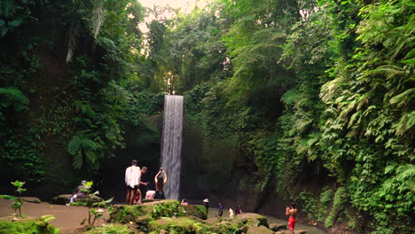 Tourists-taking-pictures-of-majestic-Tibumana-waterfall-in-Bali,-handheld