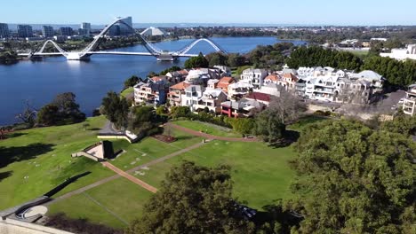 Vista-Aérea-De-Drones-Viajando-Lateralmente-Sobre-El-Parque-Costero-Del-Este-De-Perth-Con-El-Puente-Matagarup-Hasta-Una-Extensión-Más-Amplia-Del-Río-Swan