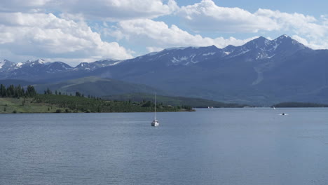 Lake-Dillon,-Colorado-USA,-Drone-Shot-of-Sailboat-in-Water-Reservoir-With-Snow-Mountain-in-Background