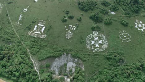 Fovant-badges-aerial-view-orbiting-above-the-set-of-regimental-badge-carvings-on-Wiltshire-chalk-hill-landmark,-UK