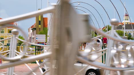 4k-60fps-cinematic-parallax-fly-by-pan-of-the-floating-Queen-Emma-Bridge-with-tourists-and-pedestrians-walking-over-it-and-cars-driving-by,-in-the-city-of-Willemstad,-Curacao