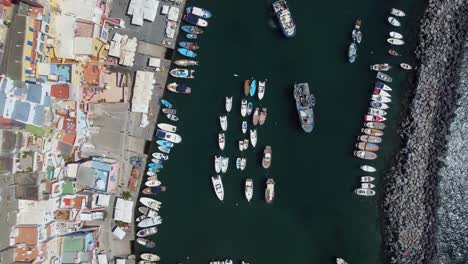 Top-Down-Aerial-View-of-Local-Marina-in-Naples,-Italy,-Fishing-Boats-by-Waterfront-Buildings-and-Breakwater-in-Mediterranean-Sea