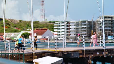 Pedestrians-and-tourists-crossing-over-the-Queen-Emma-Bridge-in-Willemstad,-Curacao