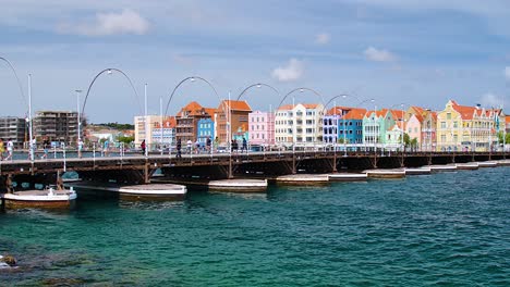 Static-shot-of-the-floating-pontoon-Queen-Emma-Bridge-and-the-colorful-Handelskade-UNESCO-houses-in-Willemstad,-Curacao