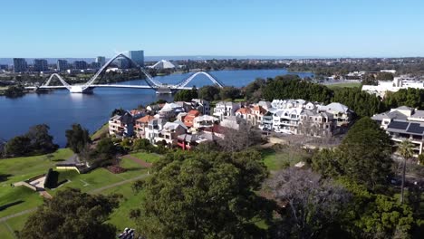 Vista-Aérea-De-Drones-Descendiendo-Sobre-El-Parque-Costero-Del-Este-De-Perth-Con-El-Puente-Matagarup-Y-El-Río-Swan