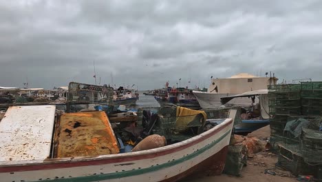 Vista-Panorámica-De-Las-Gaviotas-Que-Vuelan-Sobre-El-Puerto-De-Djerba-Con-Barcos-De-Pescadores,-Redes-Y-Banderas-Ondeantes-En-Un-Día-Nublado,-Túnez