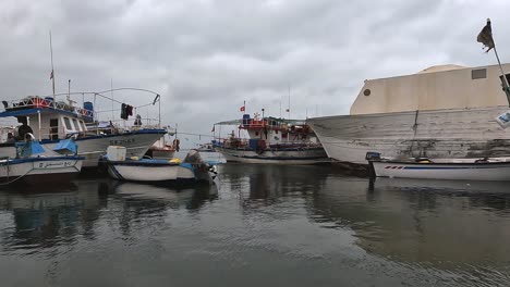 Vista-Panorámica-Del-Puerto-De-Djerba-Con-Barcos-De-Pescadores,-Redes-Y-Banderas-Ondeantes,-Túnez