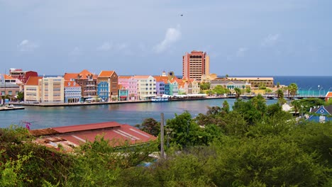 Langsamer-Umlauf-Von-Rechts-Nach-Links-über-Die-Stadt-Willemstad-Mit-Den-Ikonischen,-Farbenfrohen,-Zum-UNESCO-Weltkulturerbe-Gehörenden-Gebäuden-Der-Handelskade-In-Punda,-Curaçao