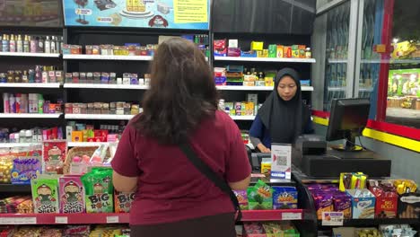 Indonesia---Jul-19,-2023-:-a-veiled-woman-serving-customers-at-the-cashier-in-the-mini-market
