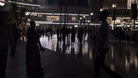 People,-tourists,-families-walking,-shopping-at-the-Dubai-mall-in-Downtown-Dubai,-UAE-with-skyscrapers-and-buildings-lit-up-at-night