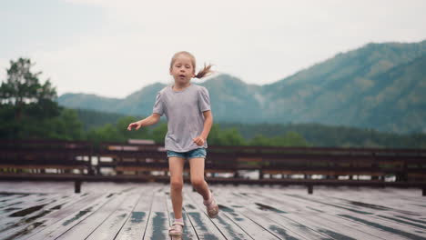 Blonde-child-runs-playing-on-wooden-board-deck-after-rain