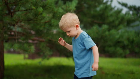 Inquisitive-toddler-boy-throws-down-pine-cone-in-hotel-yard