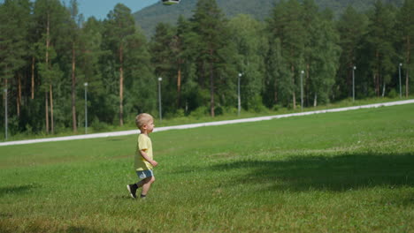 Playful-toddler-boy-runs-along-meadow-in-summer-resort-park