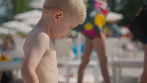 Curious-blond-toddler-boy-walks-along-public-beach