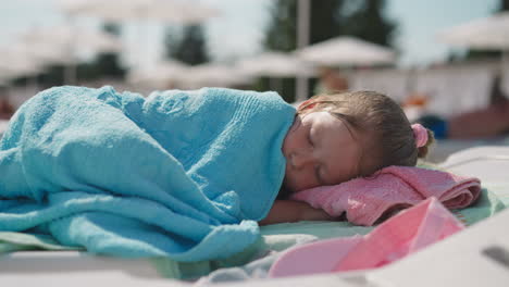 Tired-girl-sleeps-on-deck-chair-on-sunny-beach-at-resort