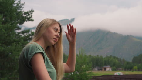 Attractive-woman-brushes-long-hair-against-misty-mountains