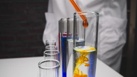Assistant-drips-yellow-reagent-into-test-tube-with-sample