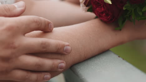 Vorsichtiger-Mann-Streichelt-Den-Arm-Der-Braut,-Die-Bei-Der-Hochzeit-Einen-Blumenstrauß-Hält