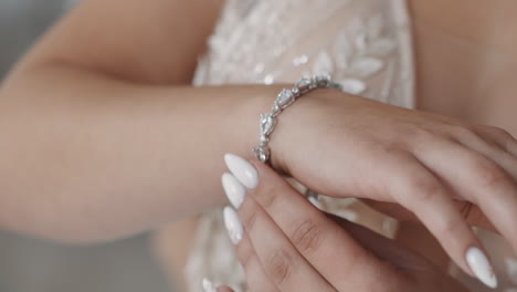 Stylish-woman-in-wedding-dress-puts-bracelet-on-wrist