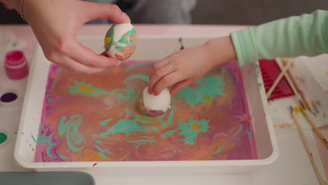Woman-and-girl-roll-eggs-in-oily-water-with-Ebru-decor-mix