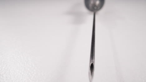 Edge-of-sterile-syringe-needle-lying-on-white-background