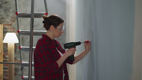 Woman-with-plastic-glasses-choose-place-to-screw-in-wall