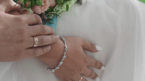 Groom-strokes-arm-of-beloved-bride-with-silver-bracelet