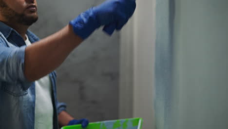 African-American-worker-in-gloves-applies-paint-on-wall