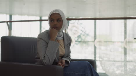 Thoughtful-black-woman-in-hijab-waits-for-partners-in-office