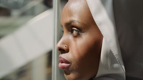 Young-black-woman-with-hijab-lifts-in-elevator-at-sunlight