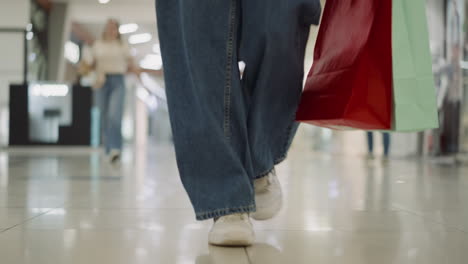 Frauenbeine-In-Weiten-Jeans-Mit-Einkaufstüten,-Die-Im-Einkaufszentrum-Spazieren-Gehen