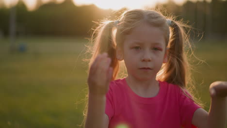 Tired-little-girl-waves-to-cool-down-in-park-at-sunset
